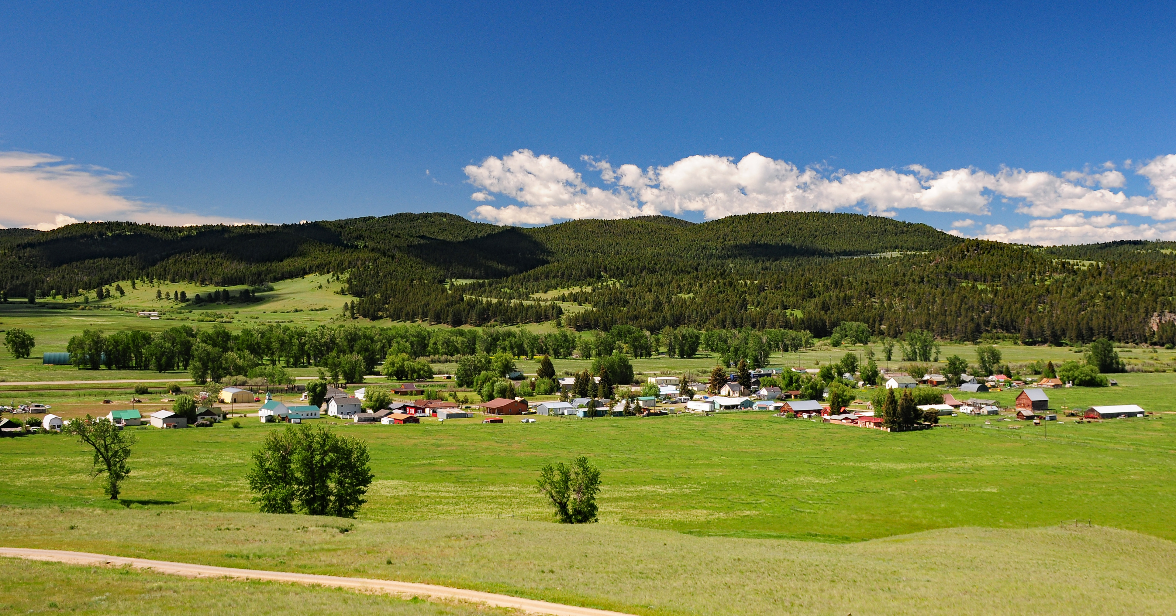 town of avon in a green field below mountains covered in trees