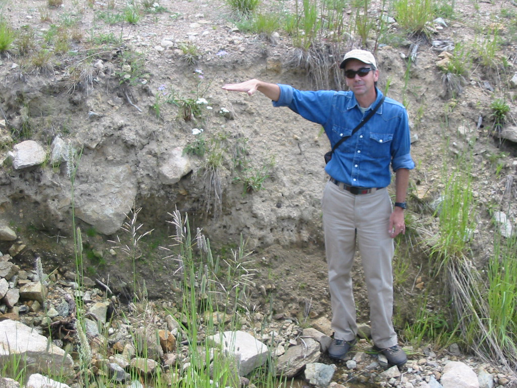 Ed Snook, a hydrologist for the Bitterroot National Forest, demonstrates just how much of the road has washed away in one area where road restoration and decommissioning is set to begin. (Photo by Ed Snook)