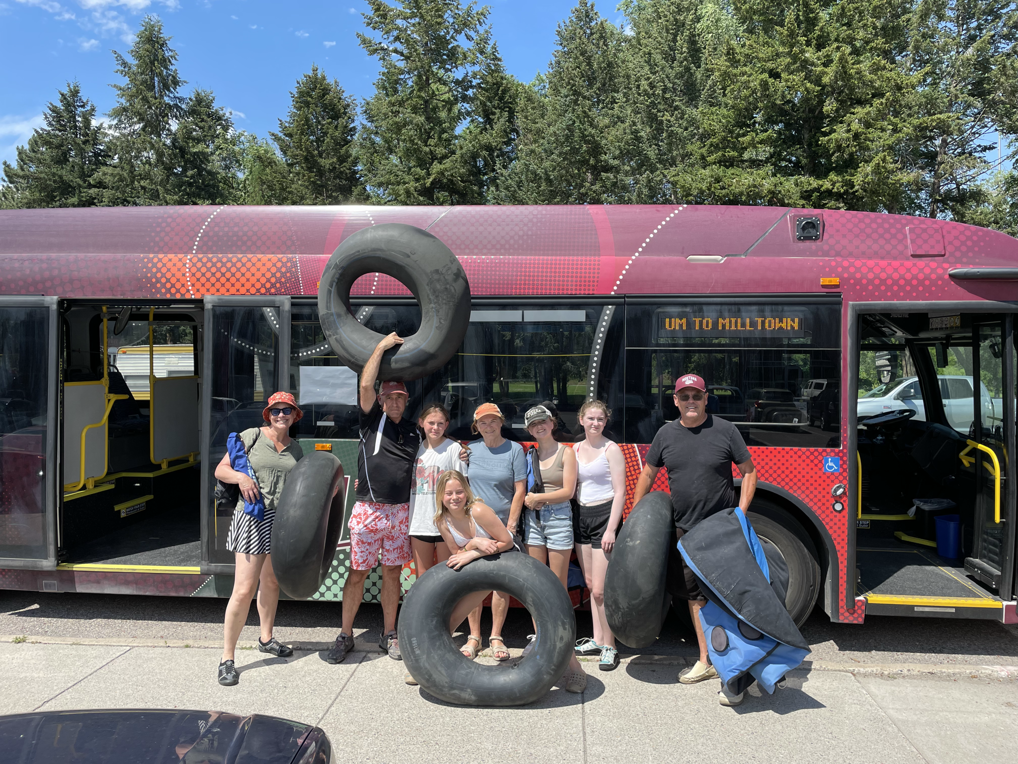 students holding inner tubes in front of bus to float the river