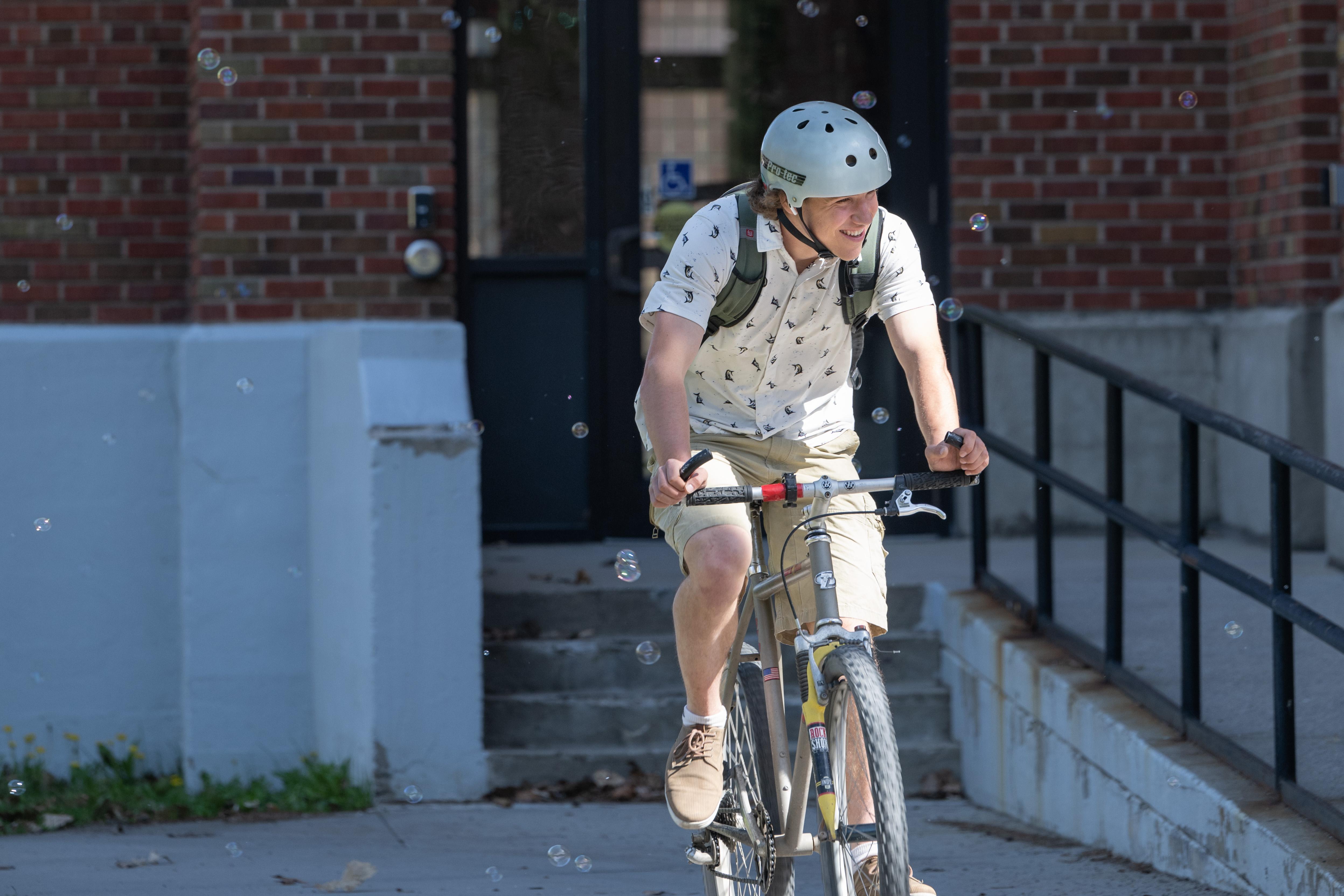 man riding bike with helmet on through bubbles