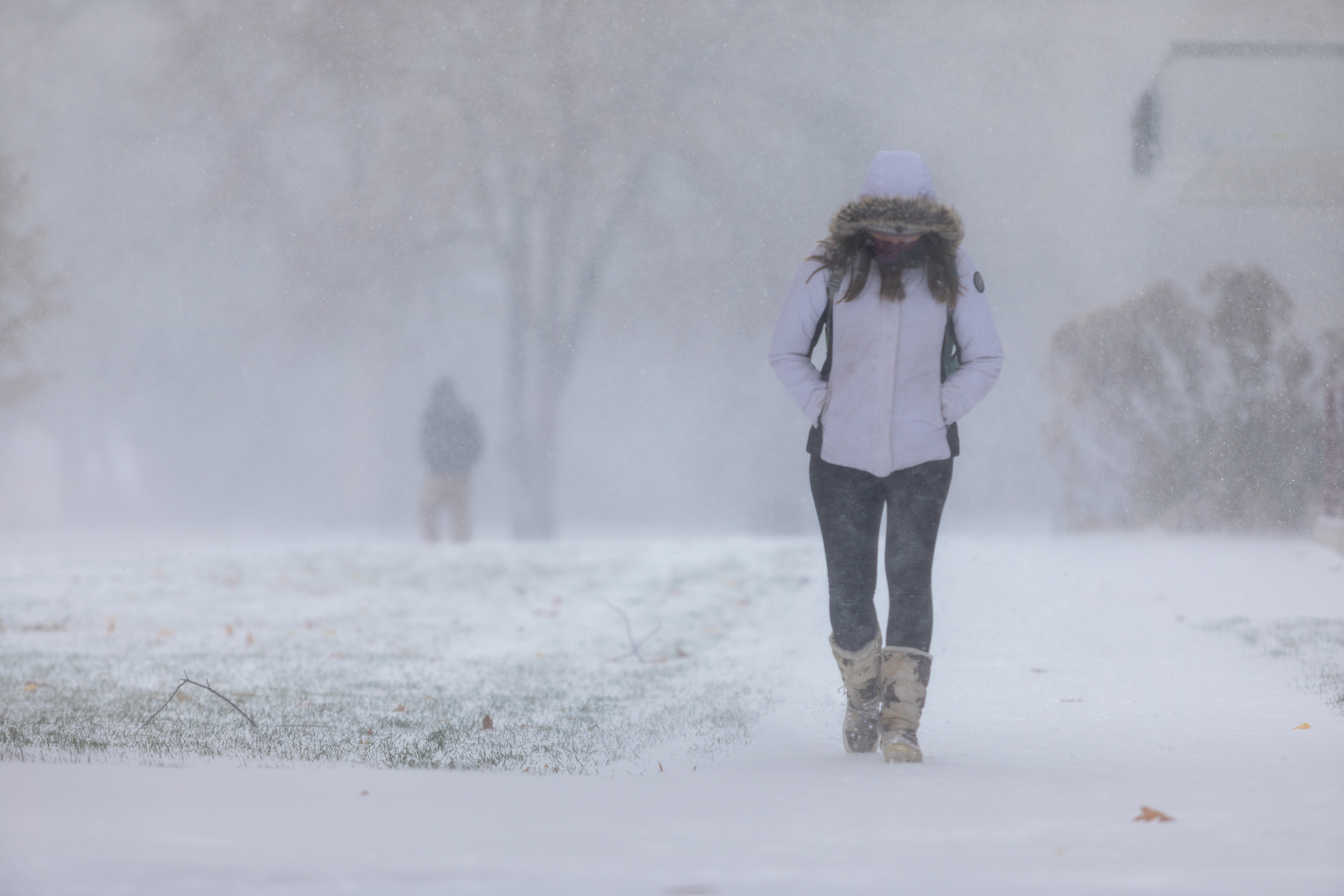 girl with hood on walking in snow storm
