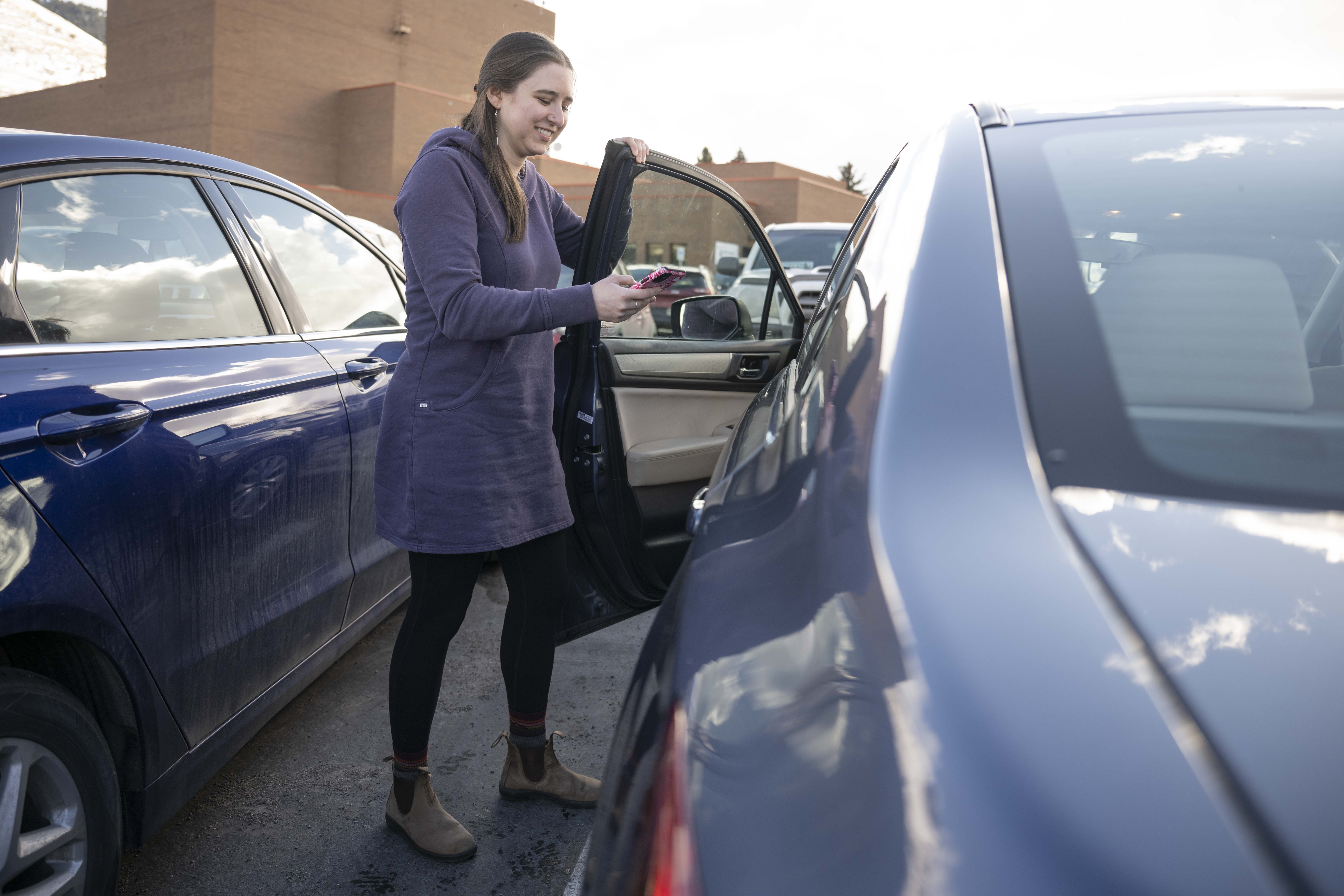 girl getting out of the car holding phone