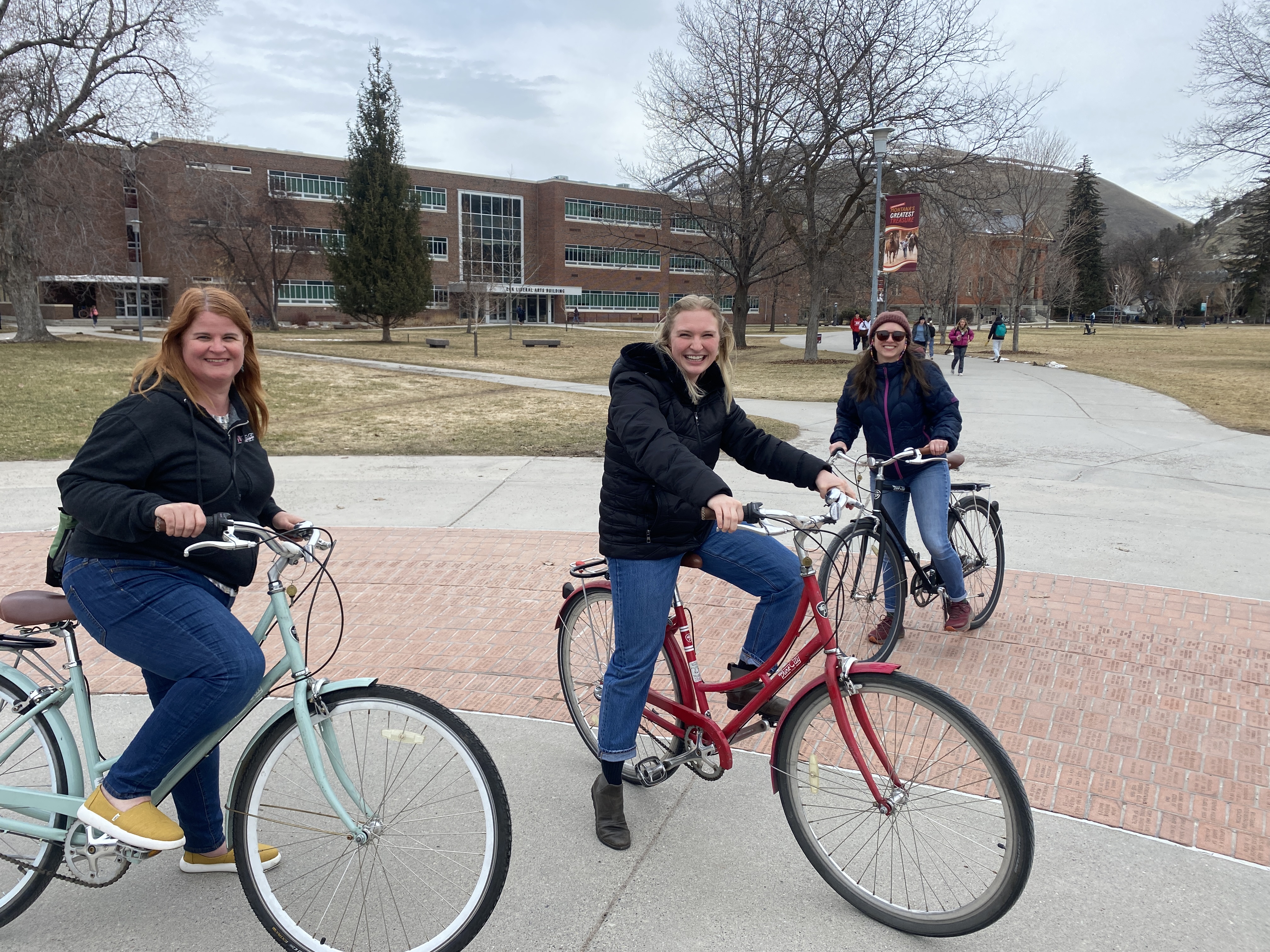 three ladies posing with their bikes on the oval