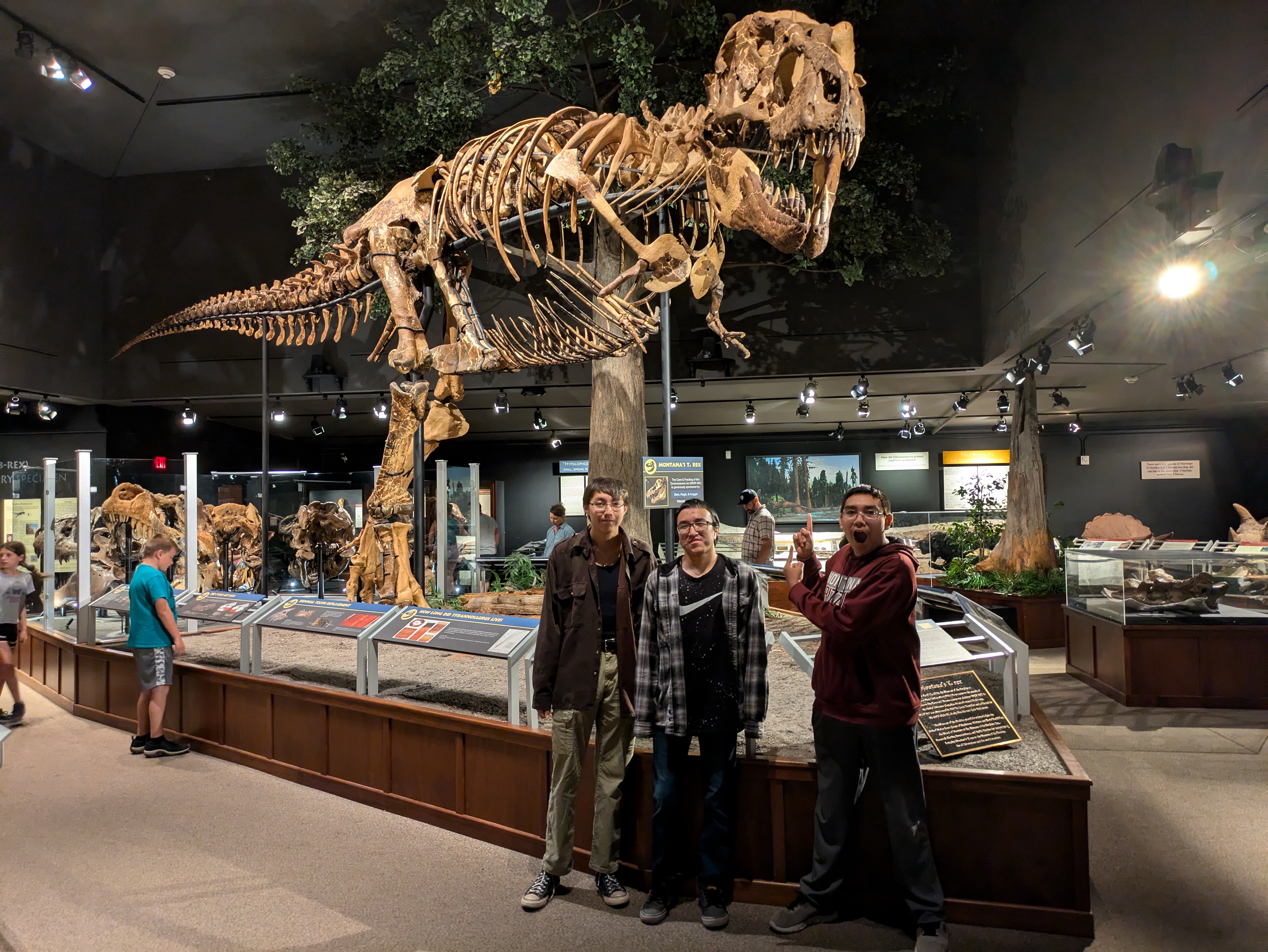 T-Rex skeleton located inside of the Meuseum of the Rockies with three of our students posing in front.