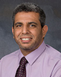 Head-and-shoulders portrait of Nady Abdal-Gaffar wearing a lavender dress shirt and patterned tie against a gray background.
